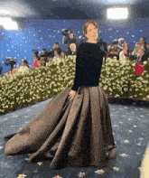 a woman in a long dress stands in front of a crowd