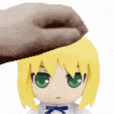 a hand is putting something on the head of a stuffed doll