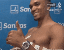 a shirtless man is giving a thumbs up in front of a blue sanitas background