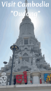a very tall building with the words visit cambodia " oudong " written on it