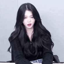 a woman with long black hair is wearing a black shirt and blue jeans
