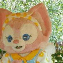 a stuffed animal dressed as a cat with blue eyes and a yellow scarf around its neck .