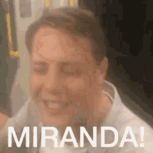 a man is sitting on a bus with his eyes closed and the words `` miranda '' written on the bottom of his face .