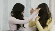 two women with long hair are playing with each other