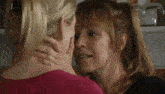 a woman in a pink shirt is kissing another woman