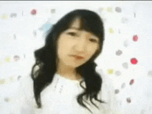 a woman with long hair is standing in front of a white wall with polka dots .