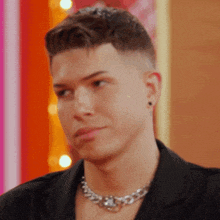 a close up of a man wearing a chain around his neck and earrings .