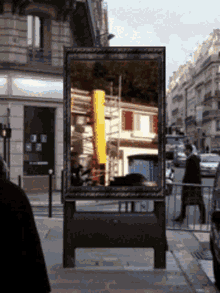 a billboard with a picture of a building and a yellow pole on it