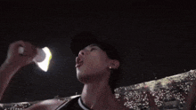 a man wearing a baseball cap is screaming in a stadium at night .