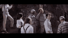a group of people in striped uniforms are standing around a man in a white shirt