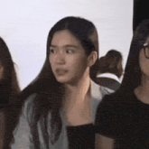 a woman with long hair looks surprised while standing next to two other women