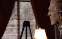 a man sitting in front of a window with blinds