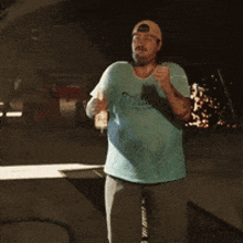 a man wearing a hat and a blue shirt is holding a bottle of beer