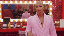 a woman with a shaved head in a pink robe