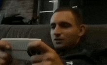 a man sitting on a couch looking at a cell phone