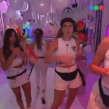 a group of women are dancing in a room with balloons and lights