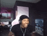 a man wearing headphones and a cross necklace is sitting in a room .