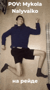 a man in a blue hoodie and black shorts is laying on the floor with the caption pov mykola nalyvaiko
