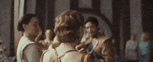 a group of people are standing in a room and one woman is holding a bottle