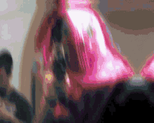 a blurred image of a person in a pink shirt