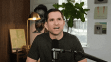 a man speaking into a shure microphone in front of a window