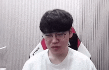 a young man wearing glasses and a white shirt with the word tiwin on the back
