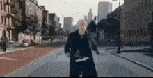 a man in a black coat is walking down a city street .