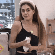 a woman wearing a headband and a black tank top holds a piece of paper