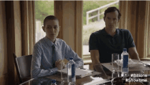 a man and a woman are sitting at a table with bottles of water