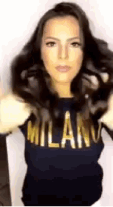 a woman wearing a milan sweater is holding her hair in her hands .