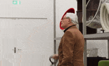 a man wearing a red hat and glasses is standing in front of a white wall