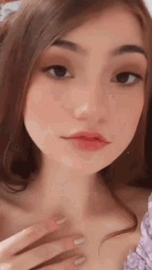 a close up of a woman 's face with a purple shirt on looking at the camera .