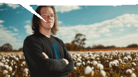 a young man stands in a field of cotton flowers with his arms crossed