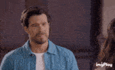 a man in a blue shirt is looking at a woman in a white shirt with imgplay written in the corner