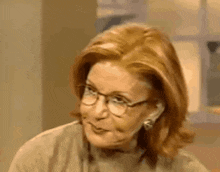 a woman with red hair and glasses is smiling