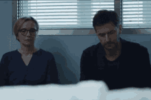 a man and a woman are sitting in front of a window