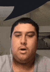 a man wearing headphones is making a funny face while looking at the camera .