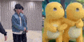 a group of people are standing next to each other in a room next to a cartoon character .