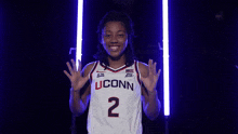 a woman wearing a white uconn jersey with the number 2
