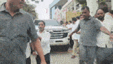 a group of men are walking in front of a white car with a license plate that says tn80 6666