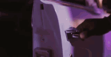 a close up of a person 's hand opening a door with purple lights behind them .