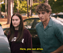 a man and a woman are standing next to each other and the man says here you can drive