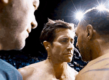 two men are standing next to each other in a boxing ring and looking at each other
