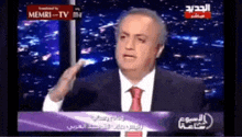 a man in a suit and tie is talking on a tv show sponsored by memri-tv