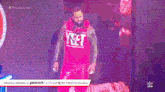 a man in a red shirt with the word net on it is walking on a stage in front of a large screen .