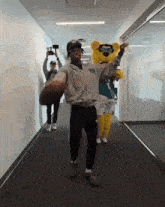 a man in a y3 hoodie holds a football in a hallway