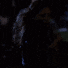 a woman in a green shirt and black jacket is running in the dark