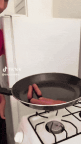 two hot dogs are being cooked in a frying pan on a stove with a tiktok watermark
