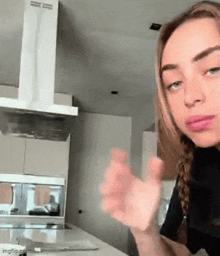 a woman is sitting at a table in a kitchen with her hands out .