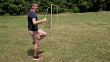 a man is standing in a grassy field holding a soccer goal .